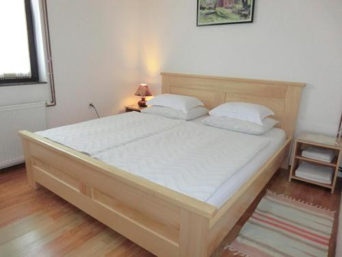 a bedroom with a large bed with white sheets at Pansion Izvor in Korenica