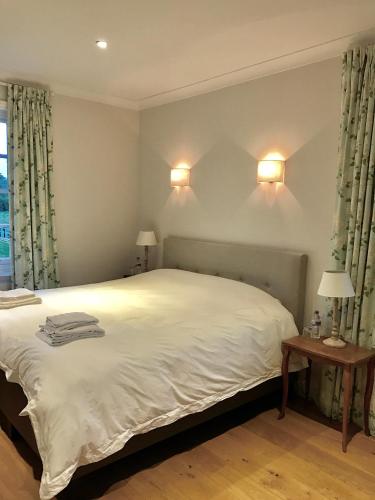 a bedroom with a large white bed with two lamps at The Old Rectory in Campsea Ashe