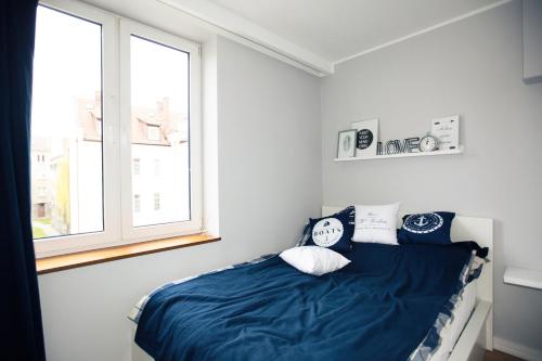 sypialnia z łóżkiem z niebieską pościelą i oknem w obiekcie Apartament Kowalska w Gdańsku