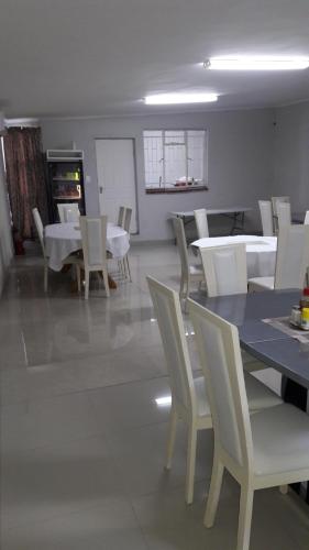 Un comedor con mesas blancas y sillas blancas. en Valley Guest House, en Pretoria