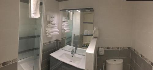 W białej łazience znajduje się umywalka i lustro. w obiekcie Logis Hotel le Mirador w mieście Portiragnes