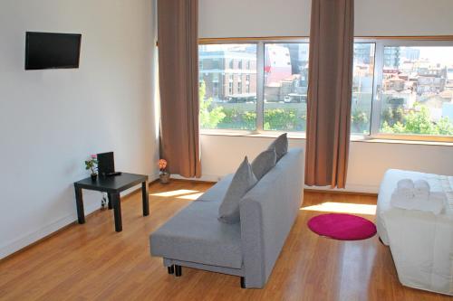 een woonkamer met een bank, een tafel en ramen bij Trindade Oporto Apartments Group in Porto