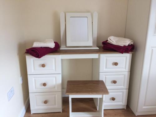 a white dresser with a mirror and a table at Greenridge Farmhouse in Crossmaglen