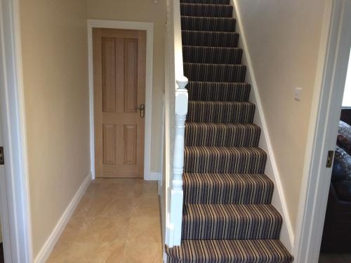a stairway leading into a hallway with a door at Greenridge Farmhouse in Crossmaglen