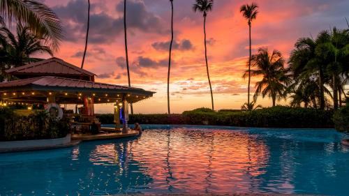 una piscina del complejo con puesta de sol en el fondo en Rincon of the Seas Grand Caribbean Hotel, en Rincón