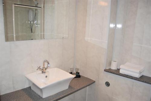a white bathroom with a sink and a shower at Kingswood Hotel in Burntisland