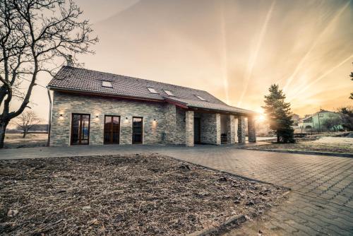 a brick house with the sun setting behind it at Apartmány U Ořecha in Bořetice