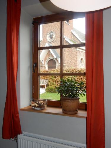 a window with a potted plant on a window sill at Vakantiehuis Haspengouw - Pastorij Mettekoven in Mettekoven