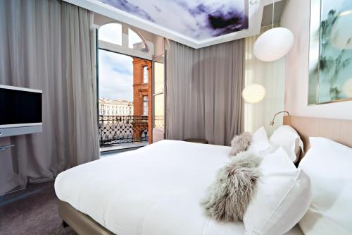 Habitación de hotel con cama blanca y ventana en Le Grand Balcon Hotel, en Toulouse