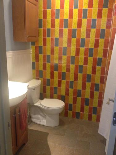 a bathroom with a toilet and a colorful tiled wall at Crossett Hill Lodge in Duxbury