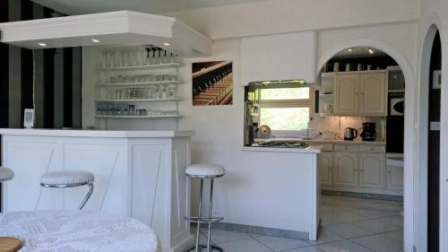 une cuisine avec des armoires blanches et un comptoir avec des tabourets dans l'établissement Le Bois Bryas, à Revin