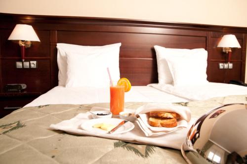 a tray of food and drinks on a bed at Hotel Rapsodia City Center in Botoşani