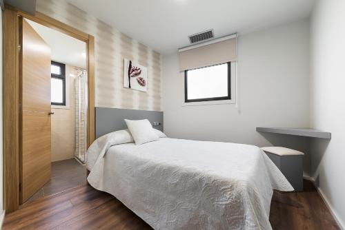 a bedroom with a white bed and a window at Pension Residencial Victoria in Santa Cruz de Ribadulla