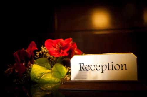 a vase of flowers next to a sign that reads reception at Hotel Rapsodia City Center in Botoşani