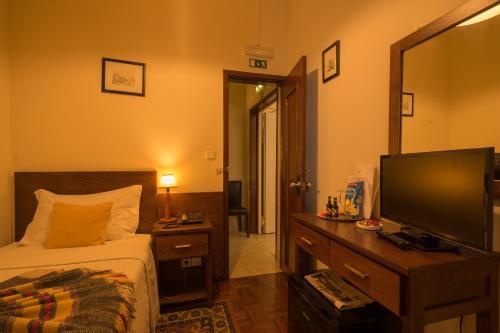 a bedroom with a bed and a flat screen tv at Pao de Acucar Hotel in Porto