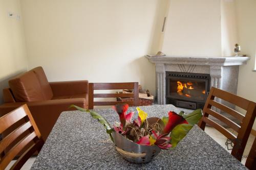 a table with a vase of flowers on it with a fireplace at Casa do Telheiro in Sabugueiro