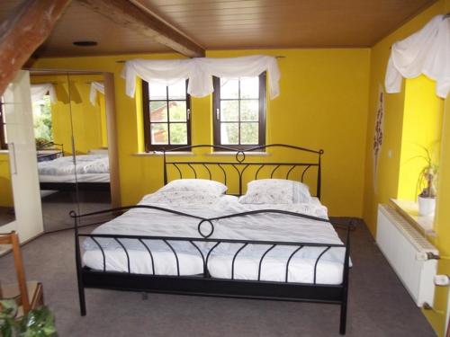 a bedroom with a bed with yellow walls and windows at Hainich-Ferienwohnung in Hörselberg-Hainich