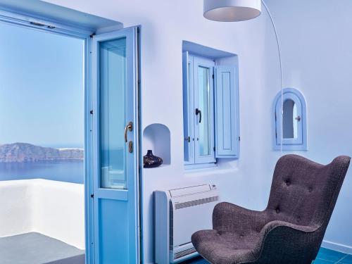 a chair in a room with a view of the water at Astra Suites in Imerovigli