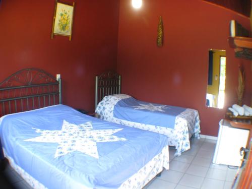 two beds in a room with red walls at Pousada Moinho De Vento in Bonito