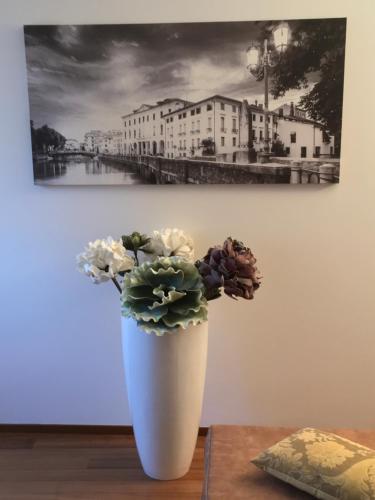 a white vase with flowers sitting on a table at La Loggia Al Duomo - Treviso in Treviso