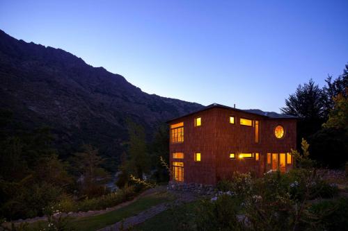 a large wooden house with lights on in a field at Hotel Altiplanico Cajón del Maipo in San José de Maipo