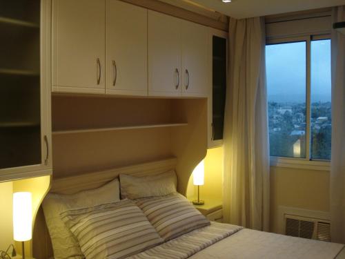 1 dormitorio con cama y ventana con vistas en Apartamento Das Palmeiras, en Porto Alegre