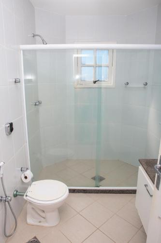 ガラパリにあるHotel Nova Guarapariのトイレとガラスのシャワー付きのバスルーム