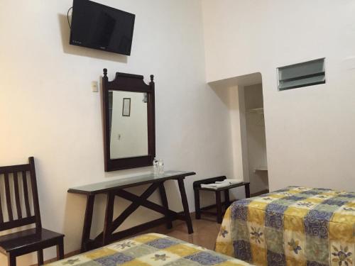 a room with a mirror and a table and two beds at Hotel de los baños in Pachuca de Soto