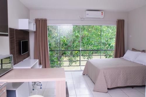 um quarto com uma cama e uma grande janela em Flat Beira Rio em Ribeira
