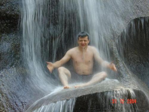 a man sitting on a rock in a waterfall at Flat Beira Rio in Ribeira
