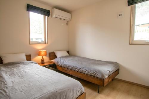 deux lits dans une chambre avec deux fenêtres dans l'établissement Koko, à Fujikawaguchiko