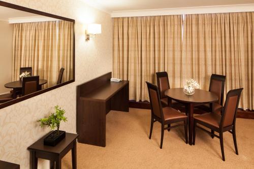 a room with a table and chairs and a mirror at Mercure Maidstone Great Danes Hotel in Maidstone