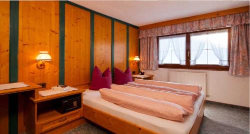 a bedroom with a bed with three pillows on it at Haus Alpenglühn in Längenfeld