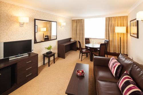 a living room with a couch and a television and a table at Mercure Maidstone Great Danes Hotel in Maidstone