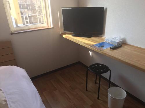 a bedroom with a desk with a television on it at Minshuku Cress in Biei