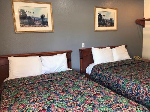 a hotel room with two beds and two pictures on the wall at Starlight Inn Canoga Park in Canoga Park