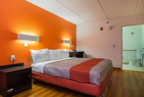 a hotel room with a bed with an orange wall at Motel 6-Tucker, GA - Atlanta Northeast in Tucker
