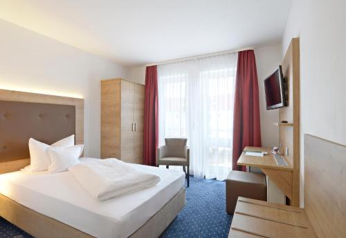 ein Hotelzimmer mit einem weißen Bett und einem Schreibtisch in der Unterkunft Hotel Poinger Hof in Poing