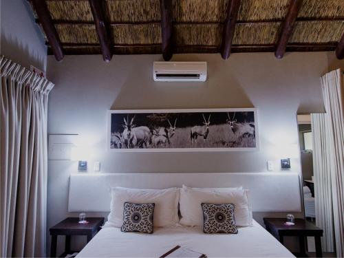 a bedroom with a bed with pillows and a picture of animals at Monate Game Lodge in Modimolle