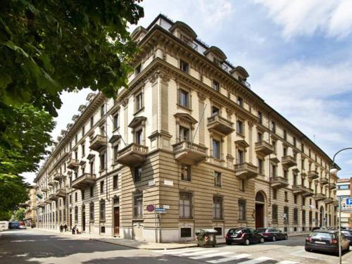 un grand bâtiment blanc avec des voitures garées devant lui dans l'établissement Artua'&Solferino, à Turin