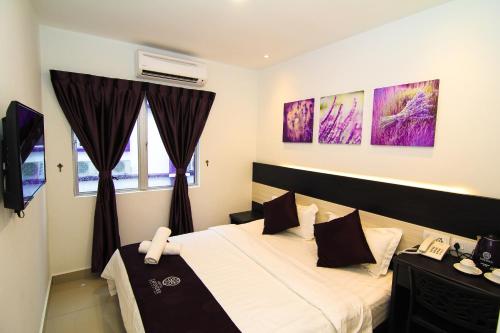 a bedroom with a bed and a phone in it at Hotel Lavender Senawang in Seremban