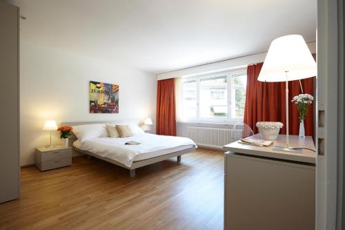 a bedroom with a bed and a window with red curtains at CITY STAY - Nordstrasse in Zürich