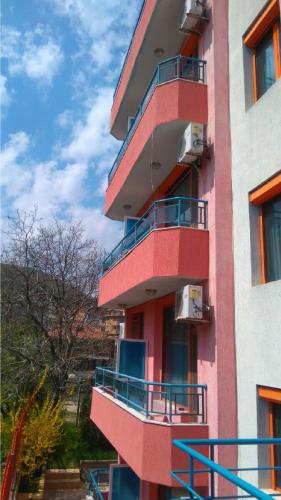 a pink building with balconies on the side of it at Family Hotel Jemelly in Obzor