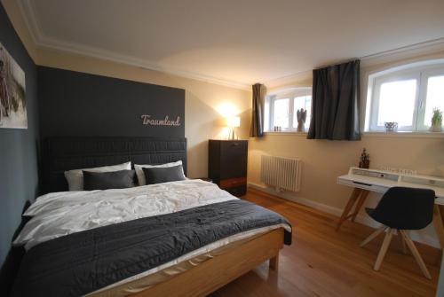 een slaapkamer met een bed, een bureau en 2 ramen bij Stadthaus Oldenburg in Oldenburg