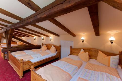 two beds in a room with wooden beams at Landhotel Zur Scheune in Röbel