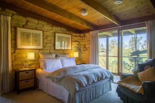 a bedroom with a bed and a stone wall at The Burrow at Wombat Bend in Dixons Creek