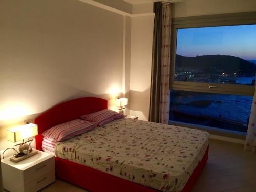 カステルサルドにあるMiramare Appartamento Rodaのベッドルーム1室(赤いベッド1台、大きな窓付)
