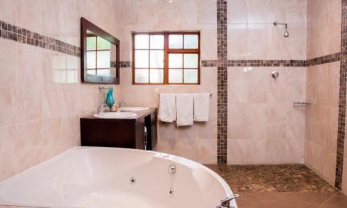 een badkamer met een bad en een wastafel bij Queen Manor Boutique Guest House in Graaff-Reinet