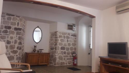 a living room with a tv and a stone wall at Apartment VASSA in Kotor
