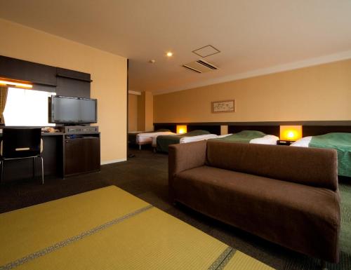 別府市にあるホテルエールのソファとテレビが備わるホテルルーム
